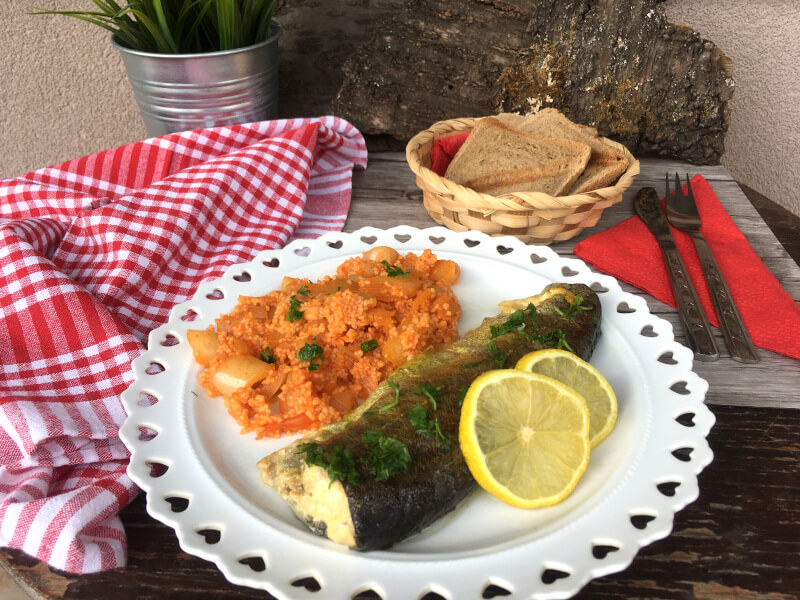 Pečena pastrmka sa povrćem i kus kusom servirana sa limunom